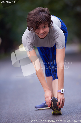 Image of woman  stretching before morning jogging