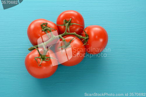 Image of Fresh tomatoes on the vine on a blue wooden surface