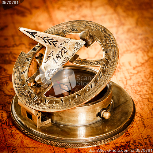 Image of Vintage compass lies on an ancient world map.