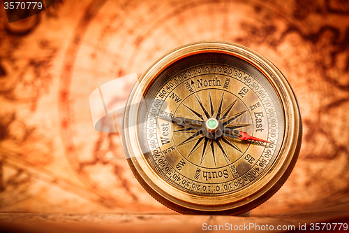 Image of Vintage compass lies on an ancient world map.