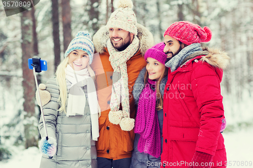 Image of smiling friends with smartphone in winter forest