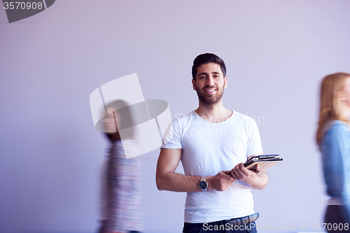 Image of student working on tablet, people group passing by