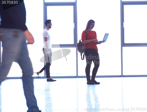 Image of student girl standing with laptop, people group passing by