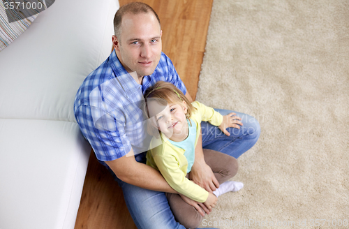 Image of happy father and daughter sitting on sofa at home