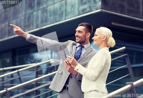 Image of smiling businessmen with tablet pc outdoors