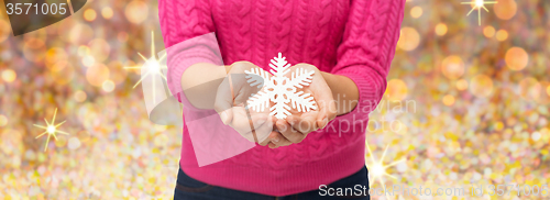 Image of close up of woman in sweater holding snowflake