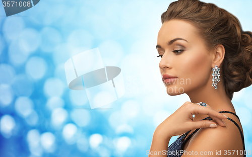 Image of woman with beautiful diamond earrings over blue