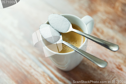 Image of close up of white sugar on teaspoon and coffee cup