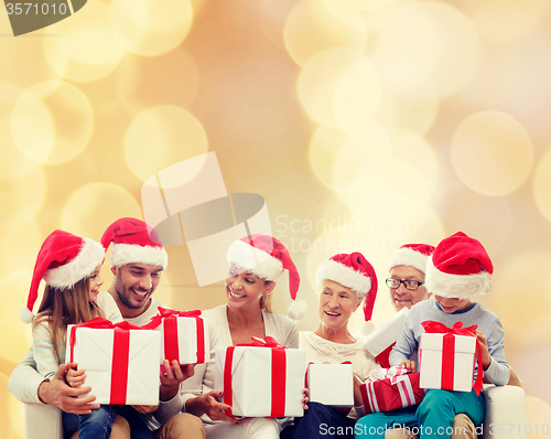 Image of happy family in santa helper hats with gift boxes