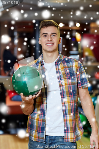 Image of happy young man holding ball in bowling club