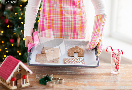 Image of closeup of woman with gingerbread house on pan