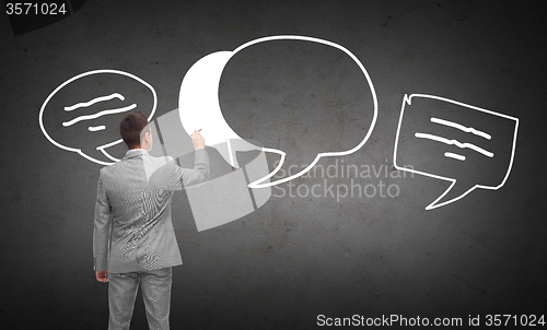 Image of businessman drawing text bubbles from back