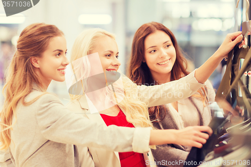 Image of happy young women choosing clothes in mall