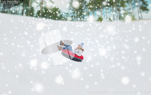 Image of happy teenage girl sliding down on snow tube