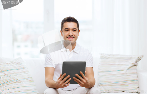 Image of smiling man working with tablet pc at home