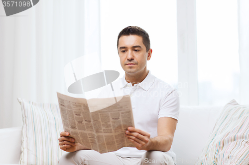 Image of man reading newspaper at home