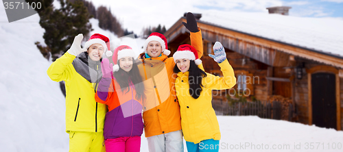 Image of happy friends in santa hats and ski suits outdoors