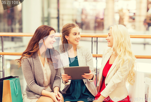 Image of happy young women with tablet pc and shopping bags