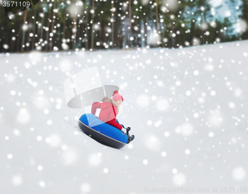 Image of happy teenage girl sliding down on snow tube