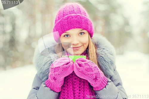 Image of smiling young woman with cup in winter forest