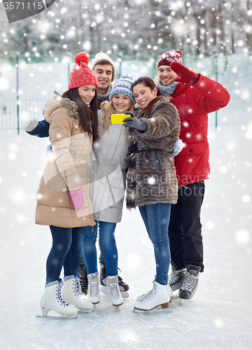 Image of happy friends with smartphone on ice skating rink
