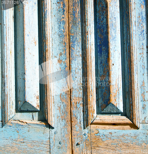 Image of dirty stripped paint in the blue wood door and rusty nail