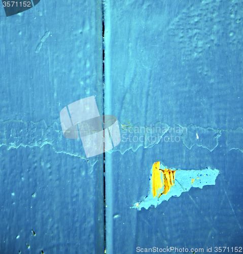 Image of dirty stripped paint in the blue wood door and rusty nail