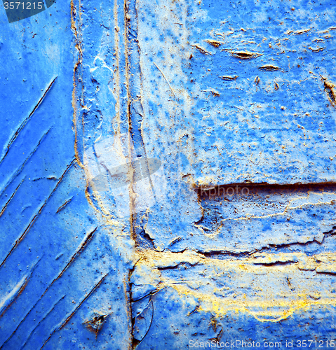 Image of dirty stripped paint in the blue wood door and rusty nail