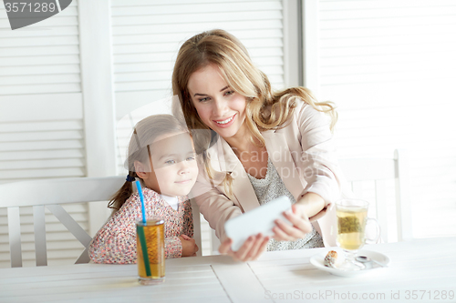 Image of happy family taking selfie at restaurant