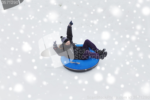 Image of happy young man sliding down on snow tube