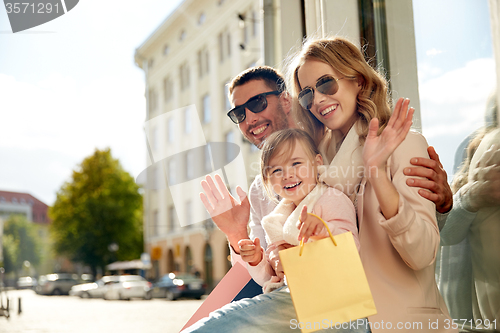 Image of happy family with child and shopping bags in city