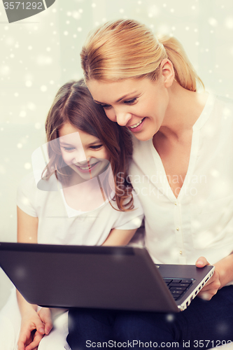 Image of smiling mother and little girl with laptop at home