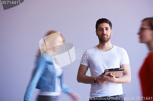 Image of student working on tablet, people group passing by