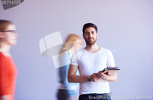 Image of student working on tablet, people group passing by