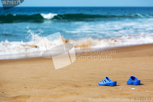 Image of Women\'s Blue Slippers on a Sandy Ocean Beach