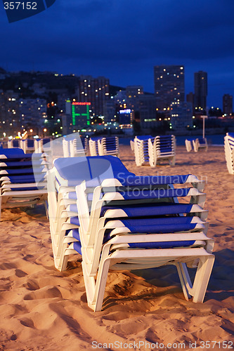 Image of Empty beach with sunbeds by night