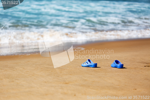 Image of Women\'s Blue Slippers on a Sandy Ocean Beach