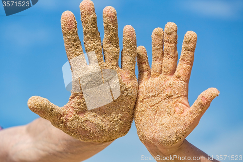 Image of Woman and Man Shows his Open Hands Covered with Beach Sand