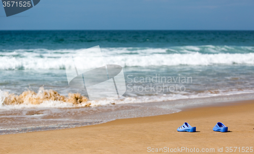 Image of Women\'s Blue Slippers on a Sandy Ocean Beach