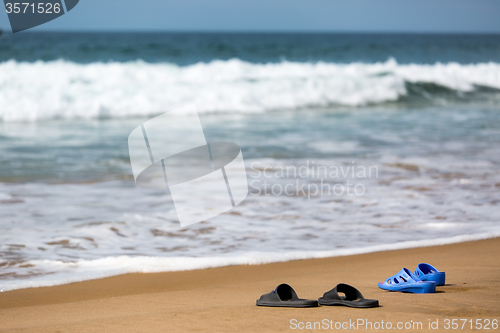 Image of Women\'s and Men\'s Slippers on a Sandy Ocean Beach