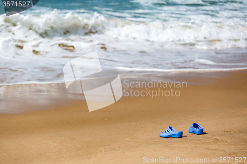 Image of Women\'s Blue Slippers on a Sandy Ocean Beach