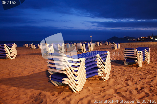 Image of Empty beach with sunbeds by night