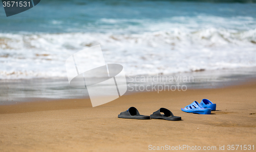 Image of Women\'s and Men\'s Slippers on a Sandy Ocean Beach