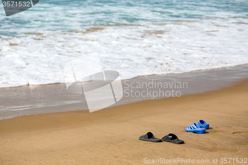 Image of Women\'s and Men\'s Slippers on a Sandy Ocean Beach