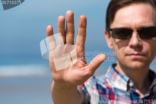 Image of Man in Sunglasses Showing Stop Sign with his Hand