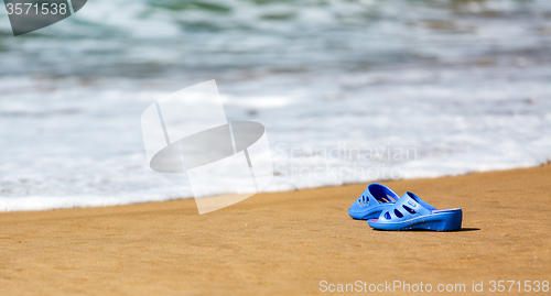 Image of Women\'s Blue Slippers on a Sandy Ocean Beach