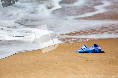 Image of Women\'s Blue Slippers on a Sandy Ocean Beach