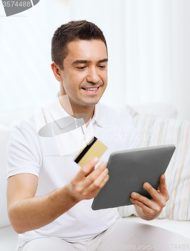 Image of smiling man working with tablet pc at home