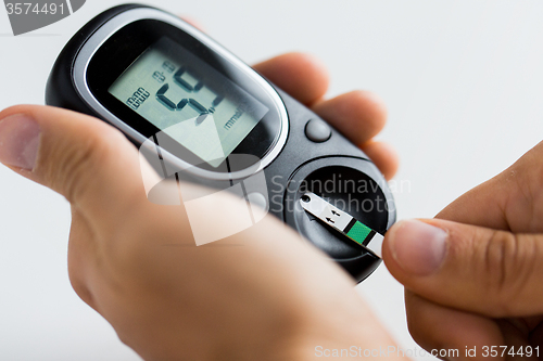 Image of close up of man checking blood sugar by glucometer