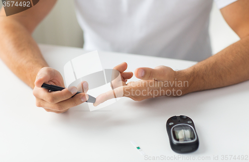 Image of close up of man checking blood sugar by glucometer